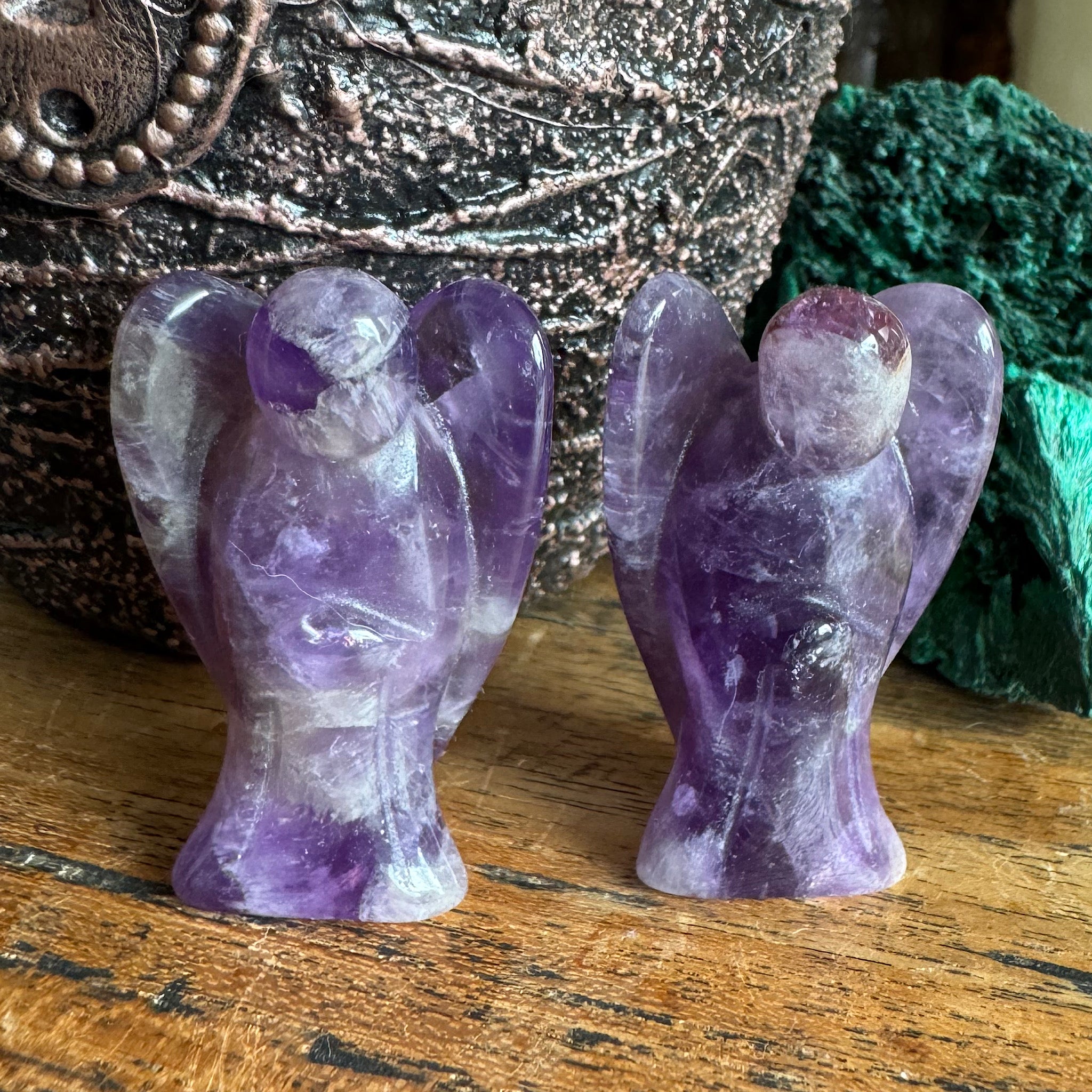 twee Amethist engel klein gepolijst op een plank voor een groene malachiet en een fles