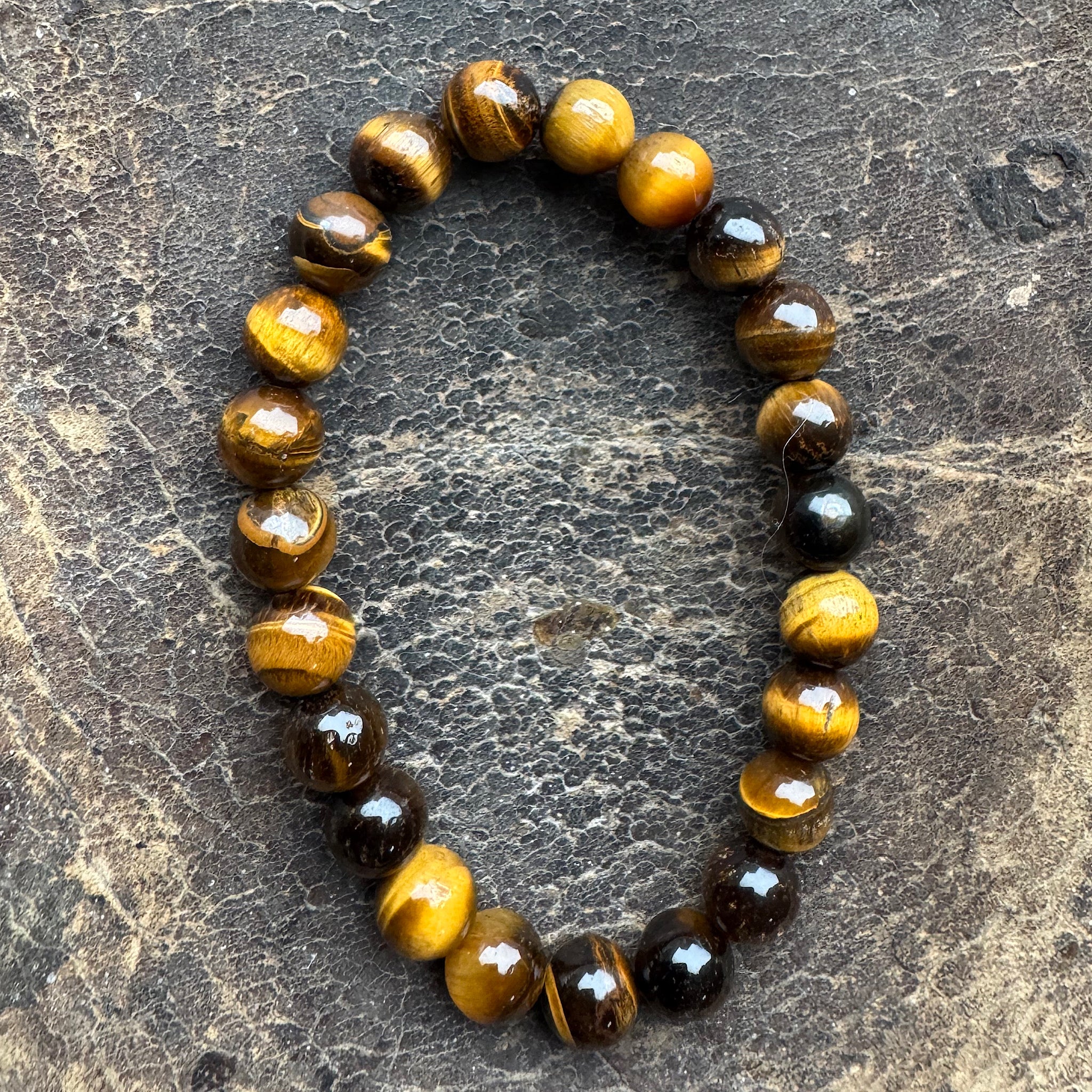 Armband TijgerOog Goud 8mm Kralen op een donker achtergrond