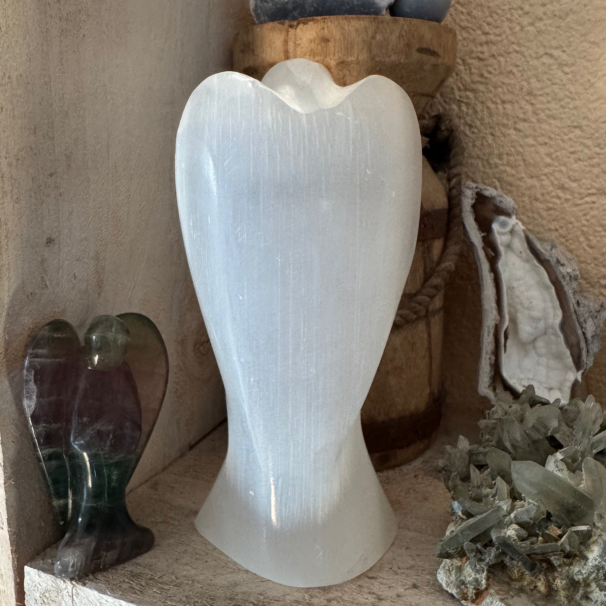 achterkant van een 16 cm hoge seleniet engel wit satijnspaat op een plank