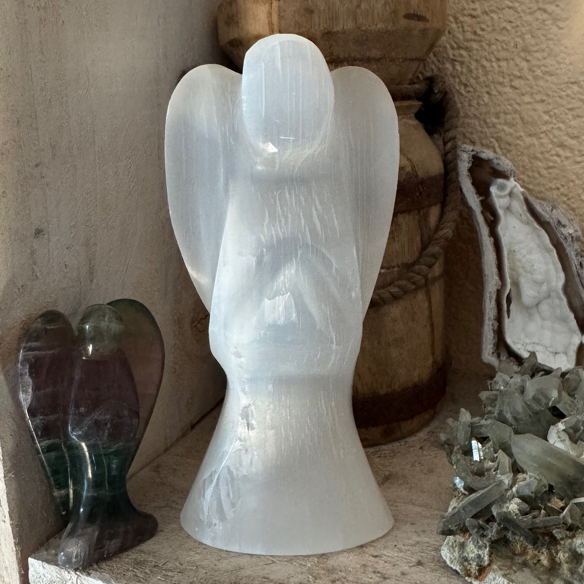 voorkant van de grote seleniet engel op een plank tussen andere edelstenen en mineralen